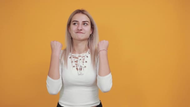 Young woman standing keeping thumbs up with arms raised, smiling for success. - Video