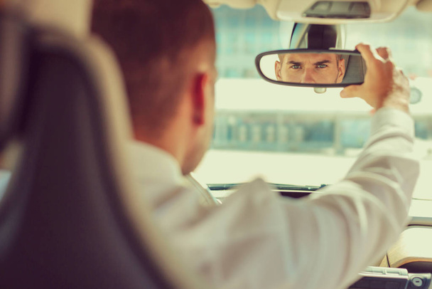 Handsome young man staring at rearview mirror - Zdjęcie, obraz