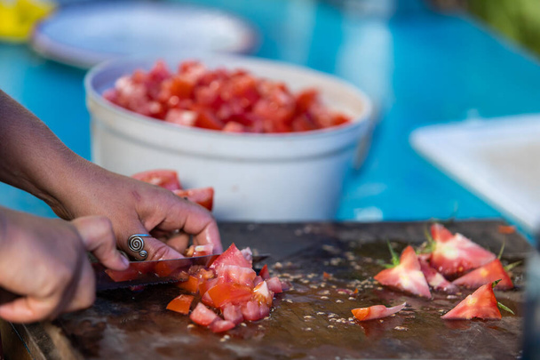 kädet leikkaamalla paljon punaisia tomaatteja
 - Valokuva, kuva