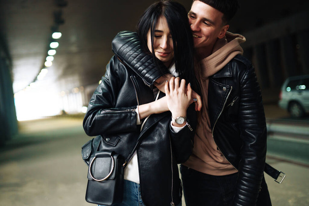 Young couple in love hug each other and have fun  in underground crossing. Couple of man and woman walking into a tunnel. Happy to be together. Love, romantic, passion, tenderness concept. - Foto, immagini