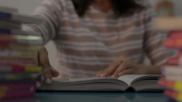 Meisje draait een pagina en het lezen van een leerboek met stapel boeken op de tafel thuis. Onderwijsconcept. - Video