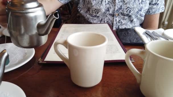 Egy férfi, aki Earl Grey teát tölt a csészéjébe egy fém teáskannából. - Felvétel, videó