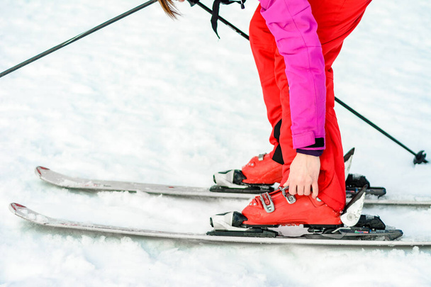 女性の足の上に赤でスキー、ブーツ、棒のスポーツセットを閉じる. - 写真・画像