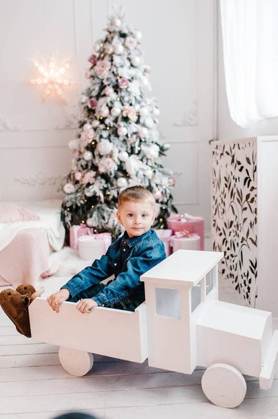 boy holding gifts box near Christmas tree, Happy New Year and Merry Christmas concept  - Fotó, kép