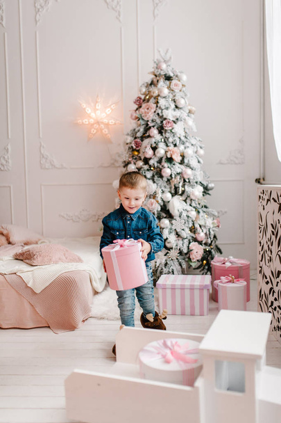 boy holding gifts box near Christmas tree, Happy New Year and Merry Christmas concept  - Фото, изображение