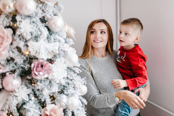 Mom hugging son near Christmas tree, Happy New Year and Merry Christmas concept  - Foto, Bild