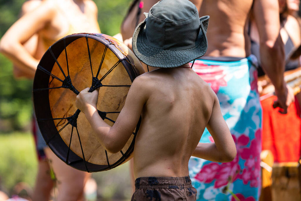 маленька дитина грає на рідному священному барабані
 - Фото, зображення