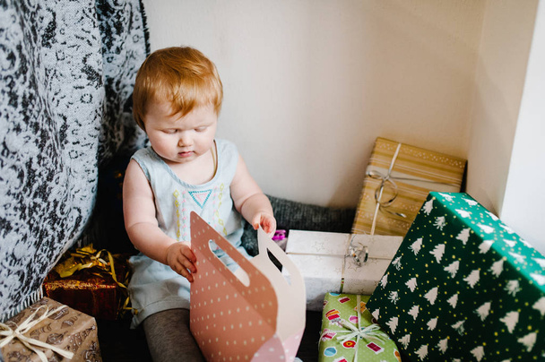 Portrait happy little girl sittings on background of gifts, festive birthday concept  - 写真・画像