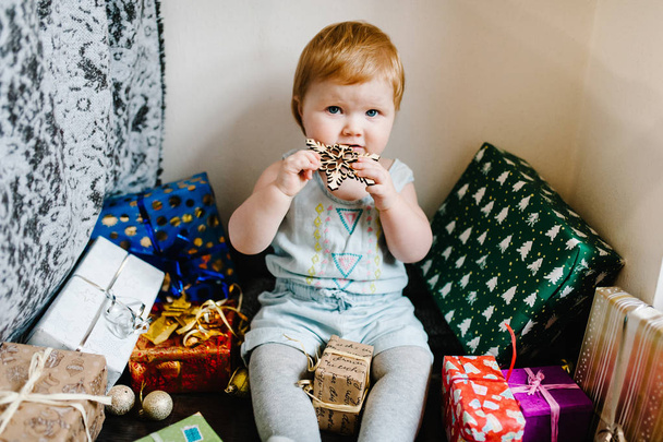 Portrait happy little girl sittings on background of gifts, festive birthday concept  - Zdjęcie, obraz