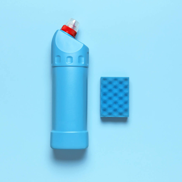 Синя пластикова пляшка для рідкого миючого засобу, миючого засобу, відбілювача, антибактеріального гелю та миючої губки на синьому фоні. Концепція прибирання будинку. Плоский вид зверху. Аксесуари для чищення
 - Фото, зображення
