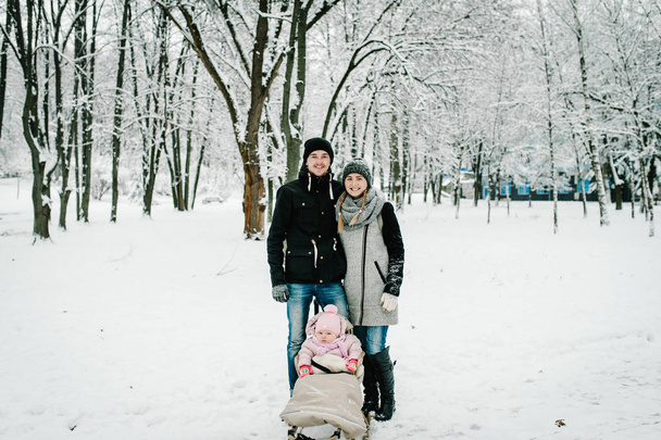 Mom, dad and daughter stand outdoors on the background winter - Fotoğraf, Görsel