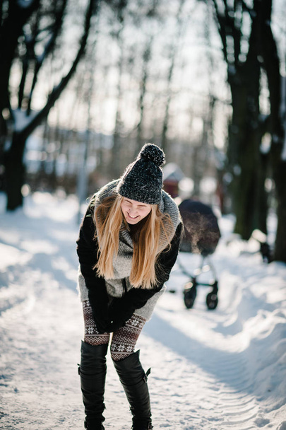 Portrait of a happy young girl jumping and enjoying snow in a winter park.  - Fotografie, Obrázek