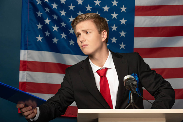elégedetlen férfi gazdaság vágólap tribunus amerikai zászló háttér - Fotó, kép