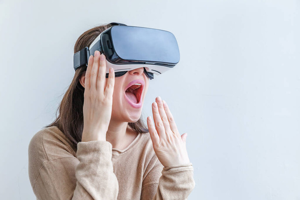 Mosolyogj fiatal nő visel virtuális valóság VR szemüveg sisak fejhallgató fehér háttérrel. Okostelefon használata virtuális valóság szemüveg. Technológia, szimuláció, hi-tech, videojáték koncepció. - Fotó, kép