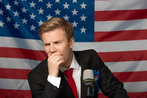 задумчивый человек на трибуне на фоне американского флага
 - Фото, изображение