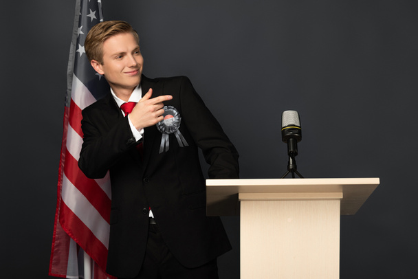 mosolygós érzelmi férfi ujjal mutogatott tribunus amerikai zászló fekete háttér - Fotó, kép