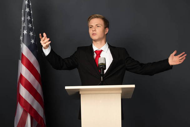 érzelmi férfi beszél tribune amerikai zászló fekete háttér - Fotó, kép