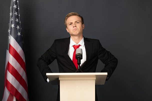 confident emotional man on tribune with american flag on black background - Photo, Image