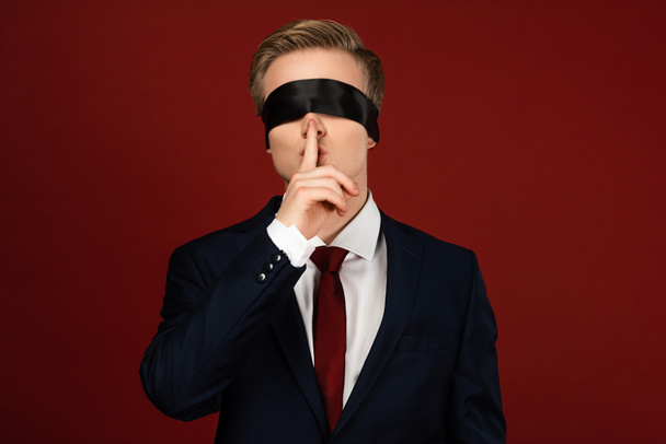 man with blindfold on eyes showing shh gesture on red background - Fotoğraf, Görsel