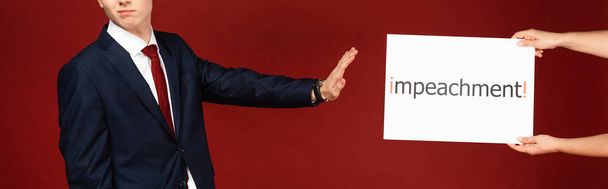 vista cortada do homem mostrando nenhum gesto para cartão branco com letras de impeachment no fundo vermelho
 - Foto, Imagem