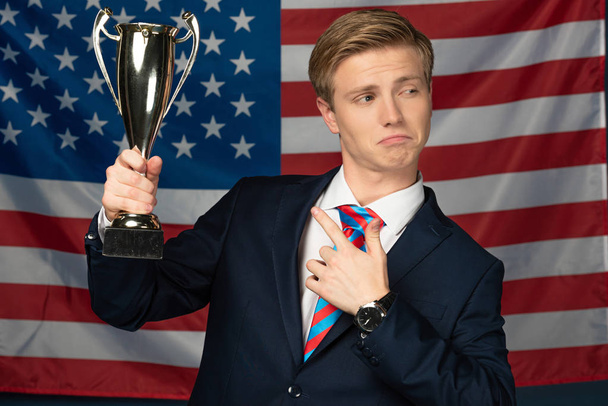 férfi ujjal mutogatás arany serleg amerikai zászló háttér - Fotó, kép