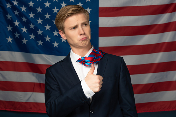 мужчина, показывающий большой палец на фоне американского флага
 - Фото, изображение