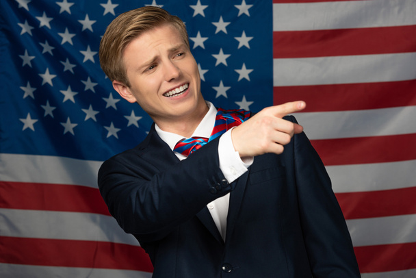 sonriente hombre señalando con el dedo sobre fondo de la bandera americana
 - Foto, Imagen