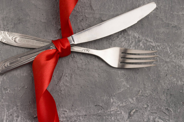 Conjunto festivo de cuchillo de cubiertos y tenedor con lazo de satén rojo, cóncavo
 - Foto, Imagen