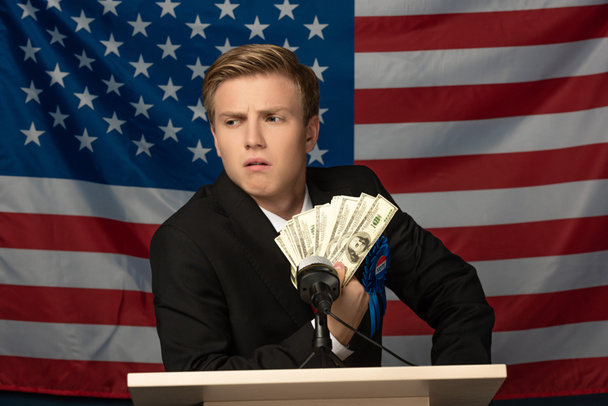 férfi kezében készpénz tribune amerikai zászló háttér - Fotó, kép