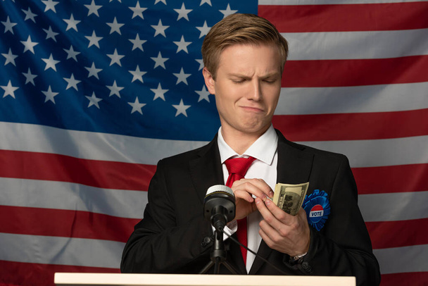 férfi kezében készpénz tribune amerikai zászló háttér - Fotó, kép