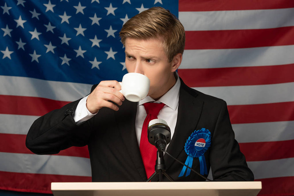 człowiek pijący kawę na trybunie na amerykańskiej fladze tle - Zdjęcie, obraz