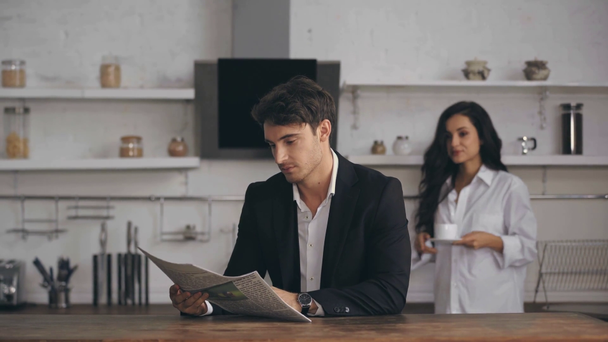 Geschäftsmann liest Zeitung und Freundin hält Tasse  - Filmmaterial, Video
