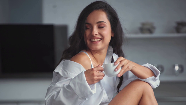усміхнена жінка в сорочці п'є каву
 - Кадри, відео