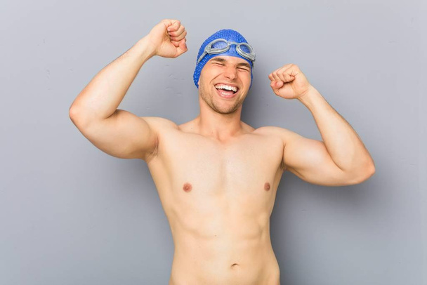 Fiatal profi úszó férfi ünnepli egy különleges nap, ugrik, és emelje fel a karját az energia. - Fotó, kép