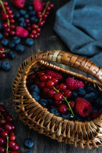 Спелые свежие черника, малина и красная смородина с плетеной стры
 - Фото, изображение