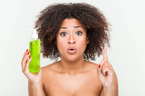 Young african american woman holding aloe vera bottle having some great idea, concept of creativity. - Photo, Image