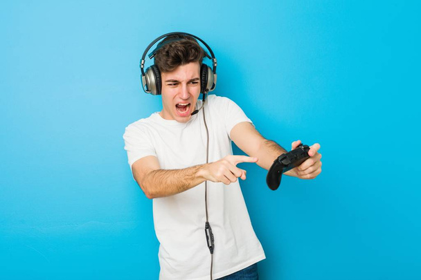 Nastolatek kaukaski mężczyzna za pomocą słuchawek i kontrolera gier - Zdjęcie, obraz