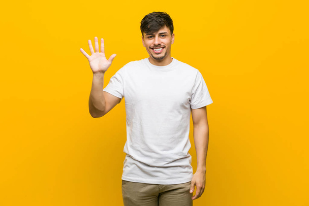 Giovane ispanico casual uomo sorridente allegro mostrando il numero cinque con le dita
. - Foto, immagini