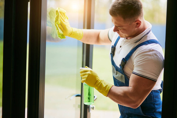Handyman pulizia finestra panoramica indossando guanti gialli
 - Foto, immagini
