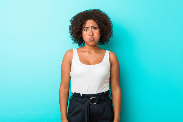 Jeune femme afro-américaine souffle les joues, a l'expression fatiguée. Concept d'expression faciale
. - Photo, image