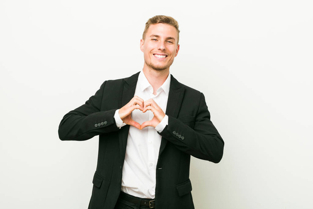 Young caucasian business man smiling and showing a heart shape with hands. - Foto, Imagem