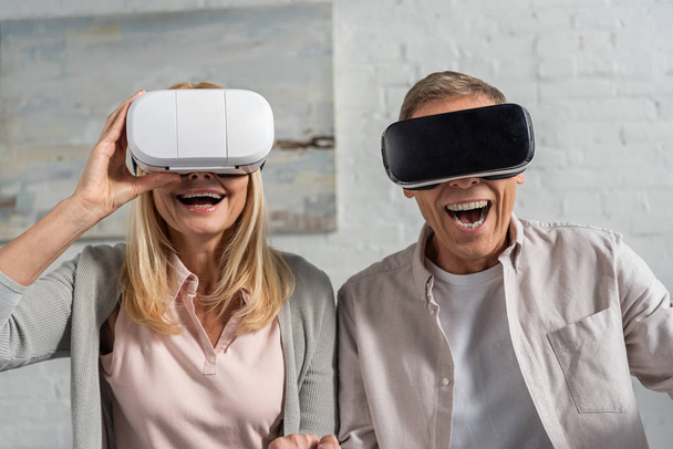 Laughing couple in virtual reality headsets at home - Fotó, kép