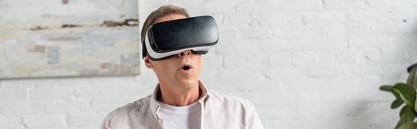 Exited man in virtual reality headset at home, panoramic shot - Fotoğraf, Görsel