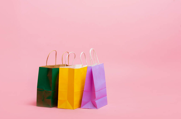 Many colorful shopping paper bags standing on pink floor. - Foto, Imagem
