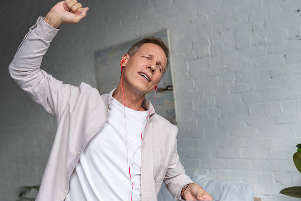 Man in earphones dancing and singing at home - Foto, Bild