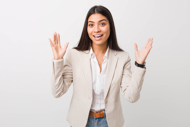 Mujer árabe joven de negocios aislada sobre un fondo blanco recibiendo una agradable sorpresa, emocionada y levantando las manos
. - Foto, Imagen