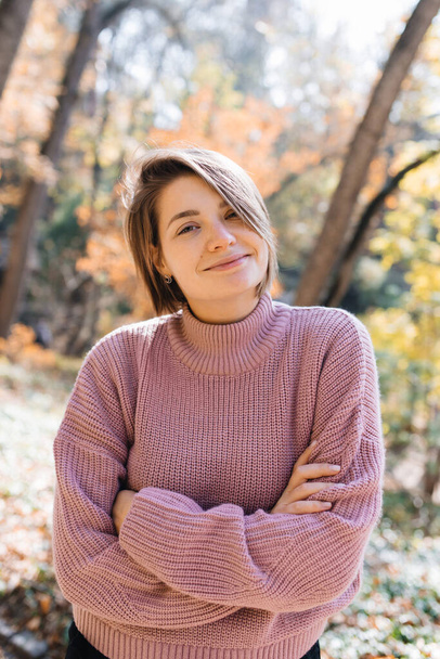 Молода жінка посміхається в осінньому лісі
. - Фото, зображення