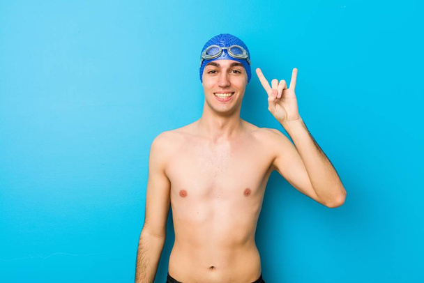 Νεαρός κολυμβητής δείχνει μια χειρονομία κέρατα ως έννοια επανάσταση. - Φωτογραφία, εικόνα