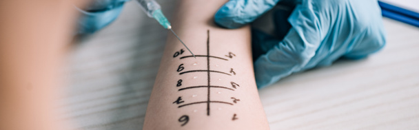 Panoramaaufnahme eines Allergologen in Latexhandschuhen, der einer Frau beim Allergietest in der Klinik eine Spritze hält  - Foto, Bild