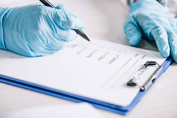selective focus of immunologist holding pen near clipboard with checklist  - Photo, image